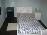 Cama individual vista desde el pie con el televisor sobre la mesa en primer plano